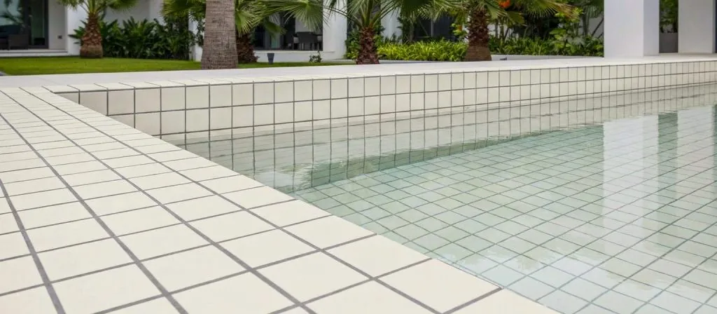 Piscina exterior con borde y vaso alicatados en azulejo cerámico color crema